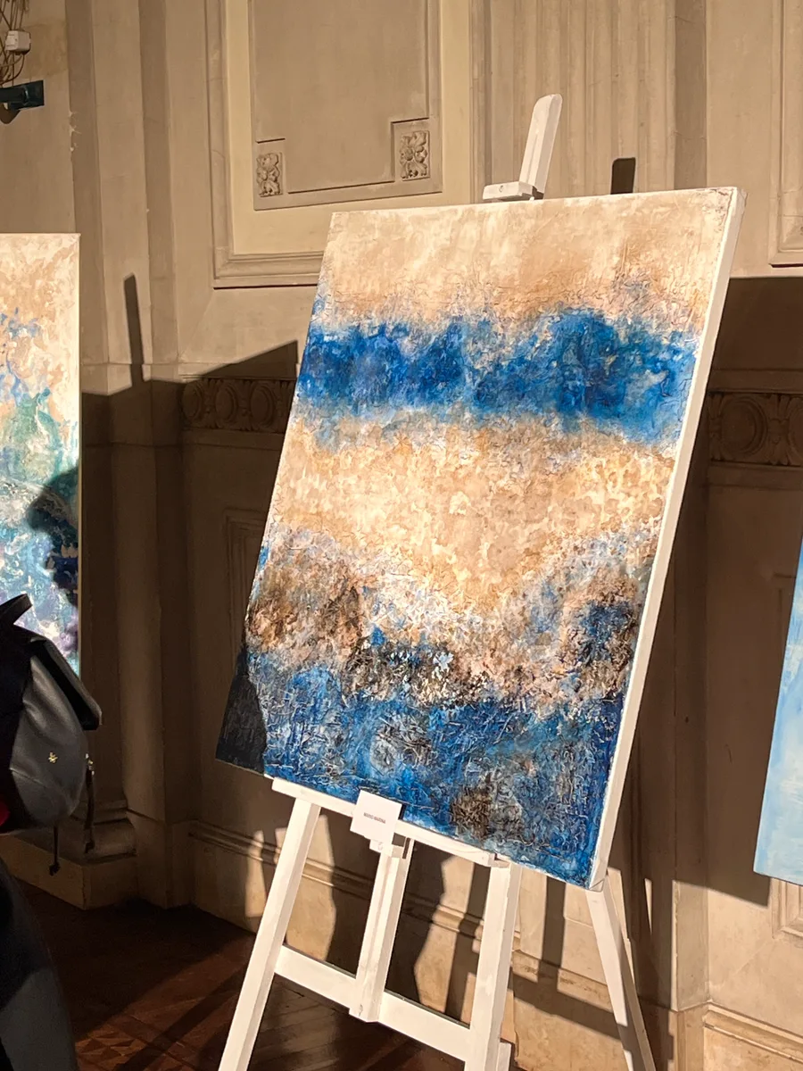 Blue and ochre painting on an easel at “101 años en colores”