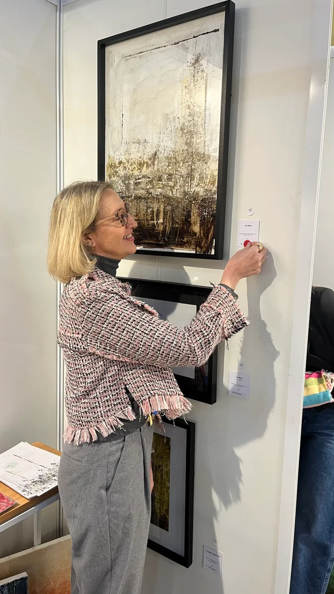 Marina Elizalde hanging a work at her booth