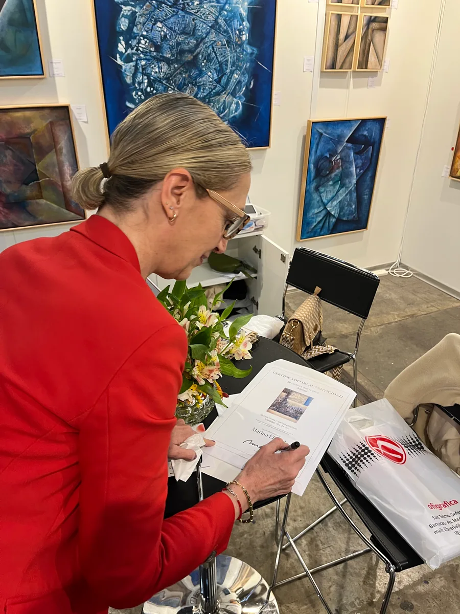 Marina Elizalde signing a catalog at her booth