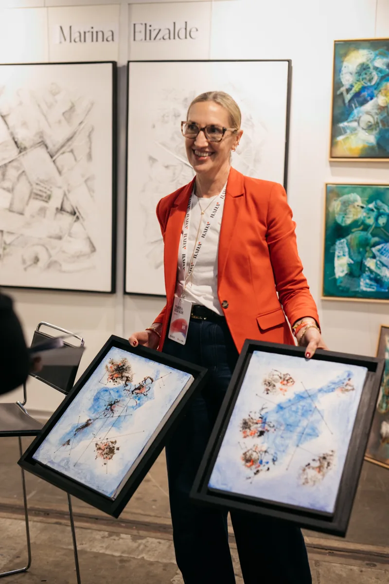 Marina Elizalde holding two framed works