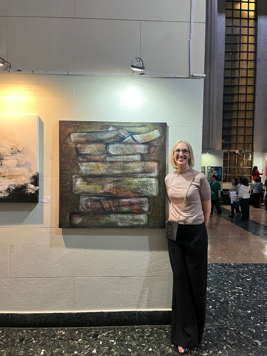 Marina Elizalde next to a painting in ochre tones